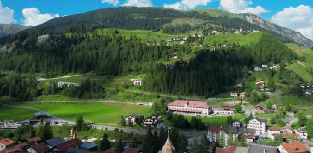 Panoramic aerial view of Bergün (Bravuogn), a charming Swiss mountain village surrounded by alpine forests and meadows.