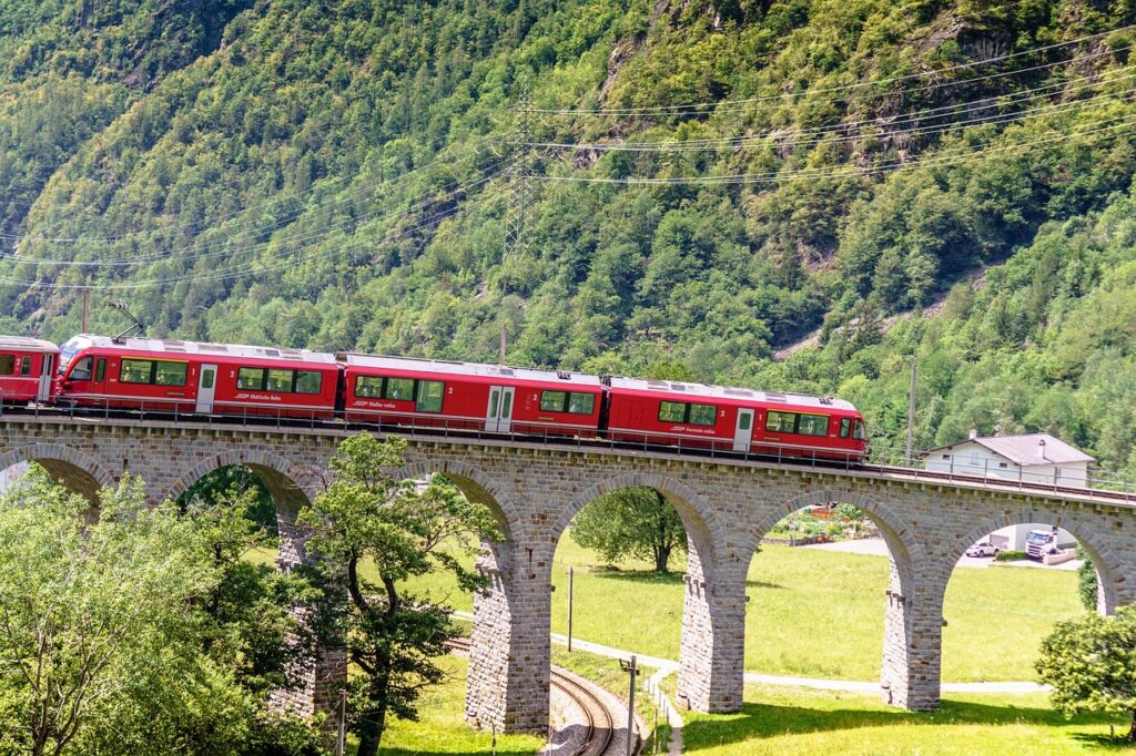 Swiss train traveling through picturesque alpine landscapes with mountains, lakes, and charming villages.