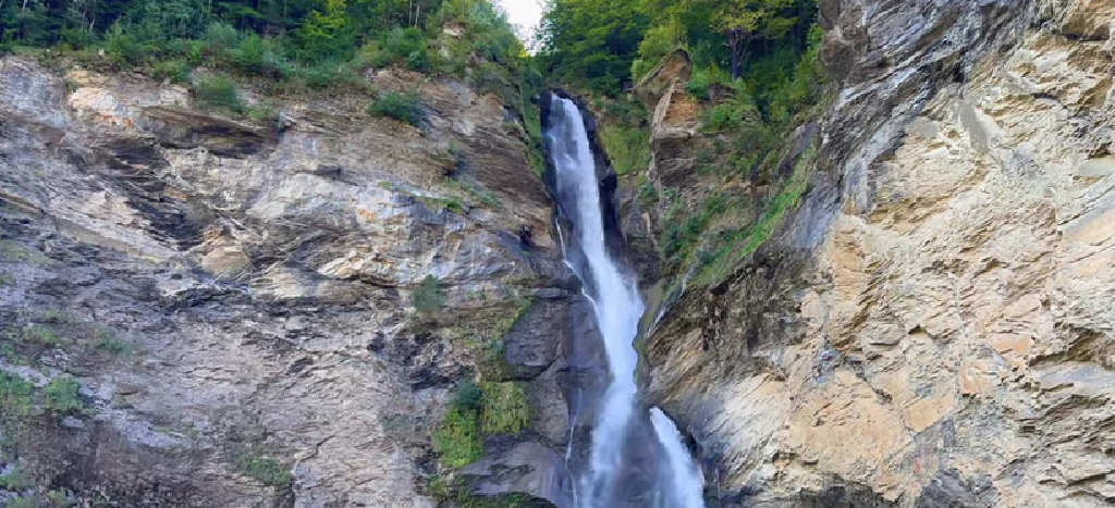 Reichenbach Falls cascading dramatically near Meiringen, a powerful yet often overlooked gem among Switzerland’s undiscovered waterfalls, surrounded by alpine cliffs and forest.