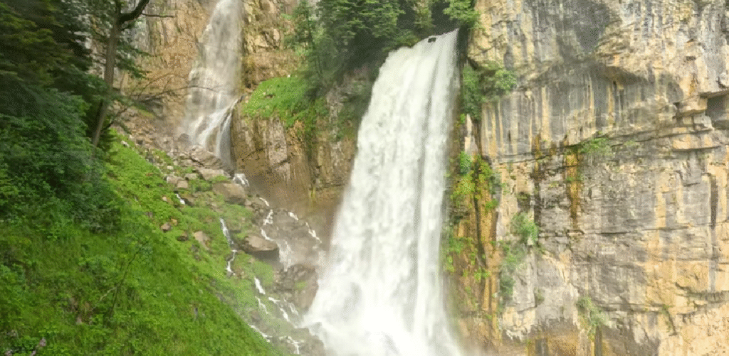 Majestic view of Seerenbach Falls plunging down steep cliffs into Walensee, one of the most impressive hidden waterfalls in Switzerland, surrounded by dramatic alpine scenery.