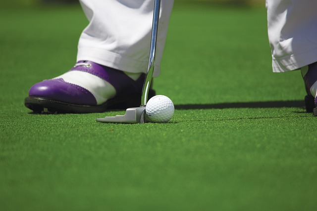 Close-up of a golfer’s feet positioned on the green as they strike the golf ball during a swing.